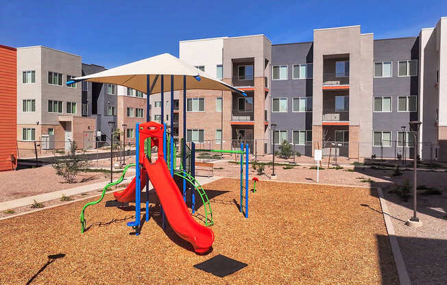 A playground with a red slide and a white canopy.