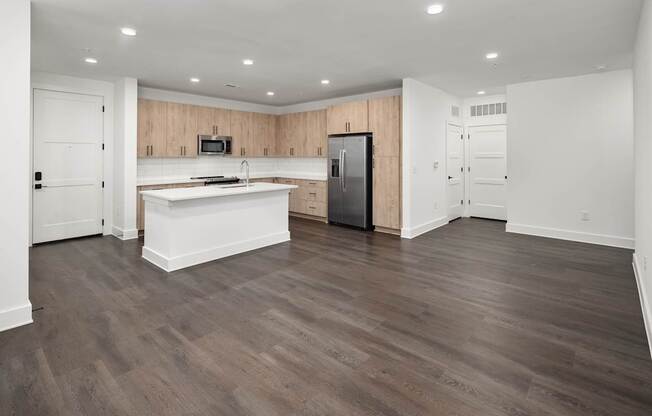 A kitchen with a refrigerator, sink, and cabinets.