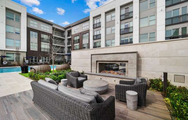 a patio with furniture and a fireplace in front of an apartment building
