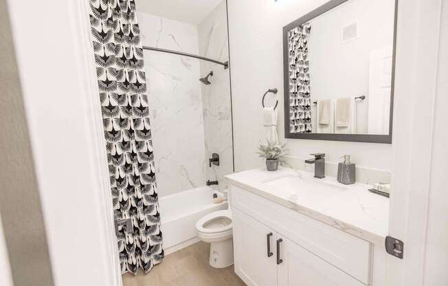 A white bathroom with a black and white shower curtain.