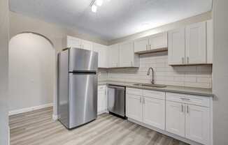 a kitchen with white cabinets and stainless steel appliances