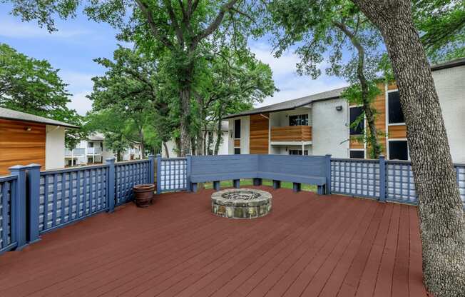 a large deck with a firepit and a blue fence