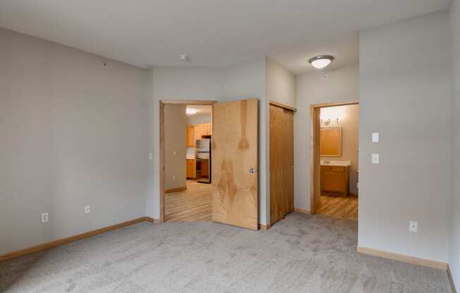 an empty living room with a door to a bedroom and a bathroom