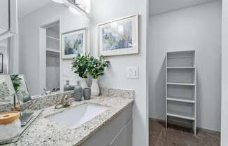 A bathroom with a sink, mirror, and shelves.