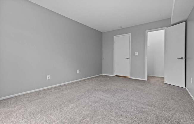 A room with three doors and carpeted floor.