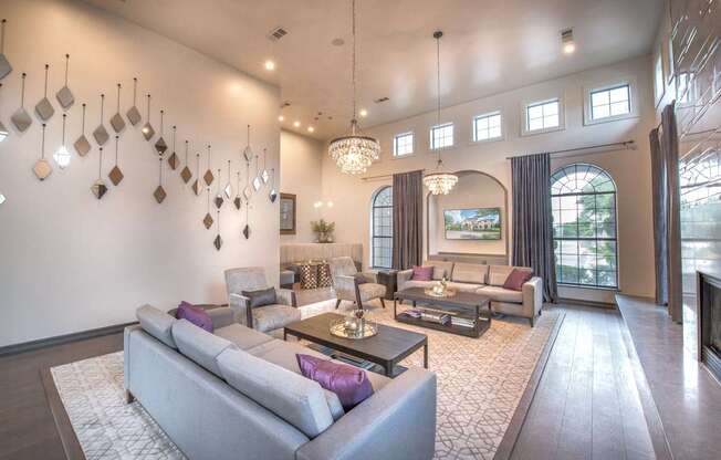 A living room with a grey couch and a chandelier.