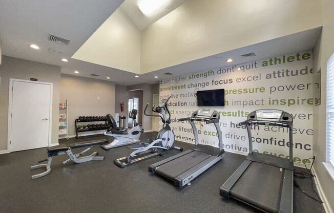a gym with weights and a monitor on the wall