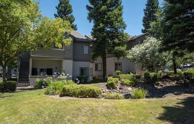 An apartment building with a well-maintained lawn and trees in the background at Sunset Summit, Rocklin, CA, 95765