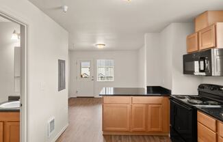 an empty kitchen with wooden cabinets and a black counter top