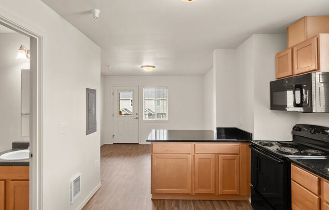 an empty kitchen with wooden cabinets and a black counter top