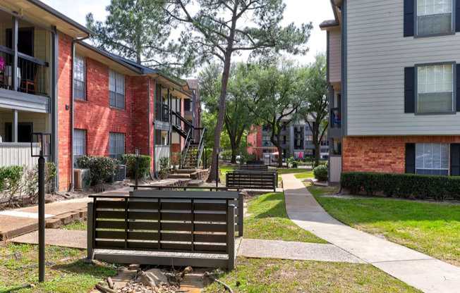 an empty park bench sitting in front of a brick building