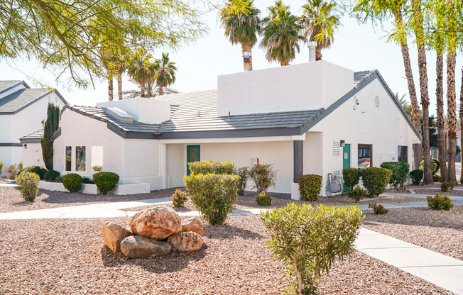 a white house with a yard and palm trees