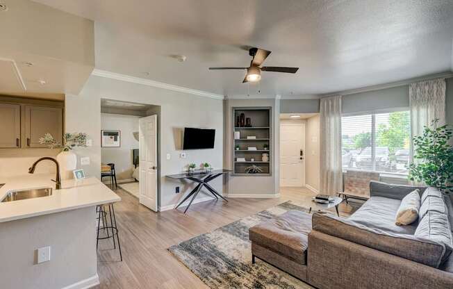 A modern living room with a brown couch and a white kitchen area.