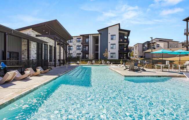 A large swimming pool in front of apartment buildings. at Bridge at Tech Crossing, Austin, TX, 78753