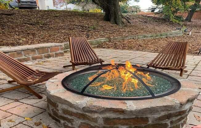 a fire pit with two wooden chairs around it