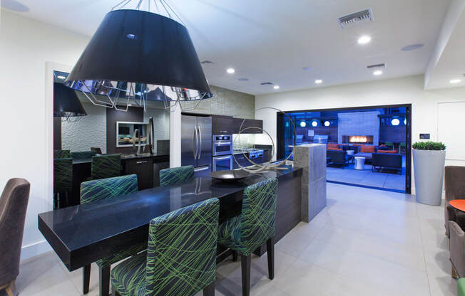 a kitchen with a long black island with a black countertop and a black chandelier