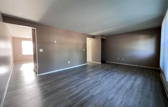 an empty living room with wood flooring and a window