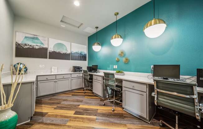 an office with desks and chairs and a wall with a blue wall with three lamps