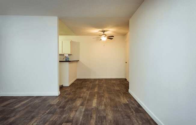 a living room with white walls and a ceiling fan