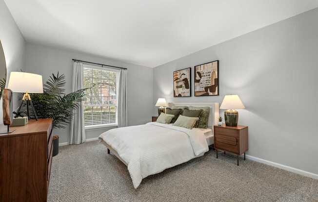 A bedroom with a bed, nightstands, and a plant.