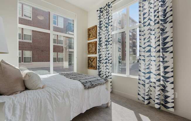 a bedroom with a bed and a window with blue and white curtains