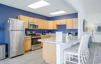 Community kitchen with stainless steel appliances, blue accent wall, and a counter with chairs for dining