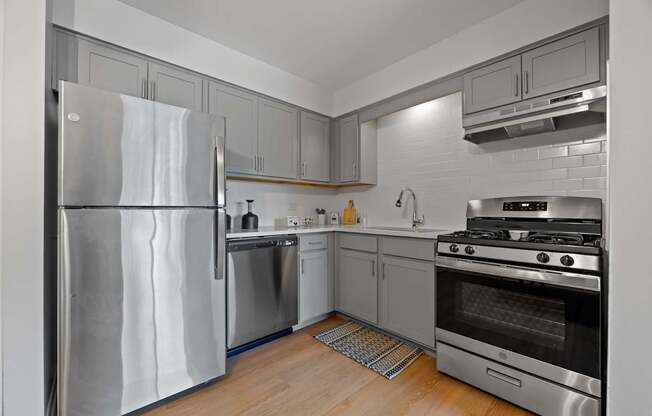 A modern kitchen with stainless steel appliances and wooden flooring.