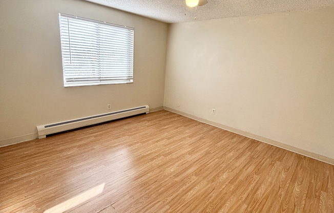 Bright, spacious room with elegant wood flooring and a modern ceiling fan, creating a welcoming atmosphere.