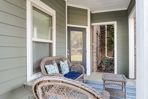 A patio with a wicker chair and a cushion.