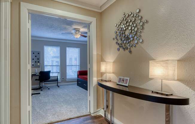 a living room with a ceiling fan and a desk with two lamps