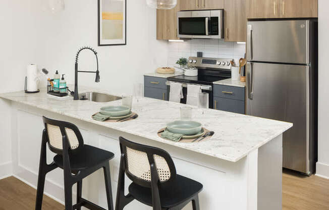 A kitchen with a white countertop and black barstools.