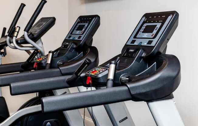 a row of treadmills in a gym with a tv on the wall