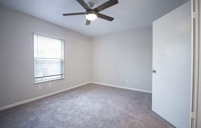 an empty room with a ceiling fan and a window