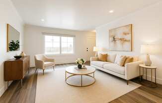 A living room with a white couch, a coffee table, and a large painting on the wall.