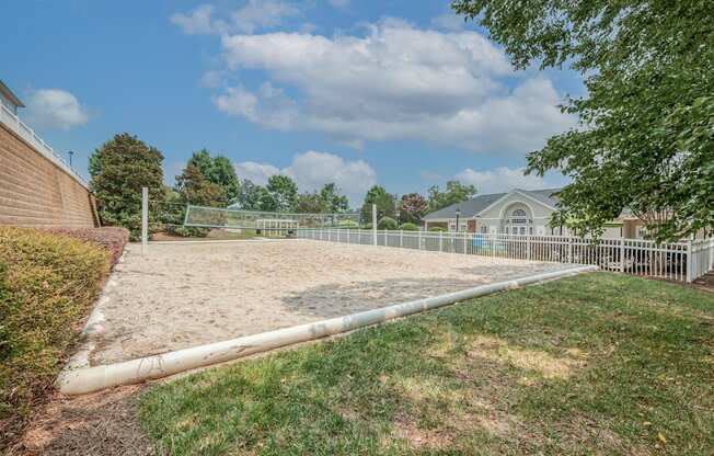 A large, empty sand pit sits in the middle of a grassy area.