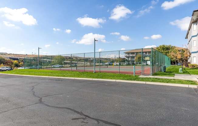 a tennis court in front of a building with a green fence  at Shoreline Village, Richland