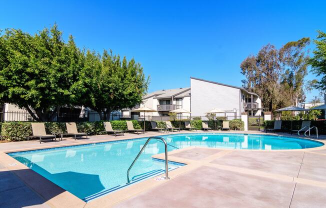 A swimming pool surrounded by trees and lounge chairs.