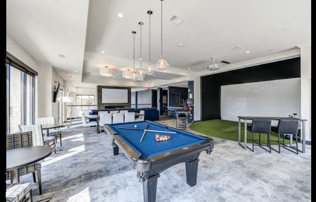A pool table is in the middle of a room with a green rug and a dining table.