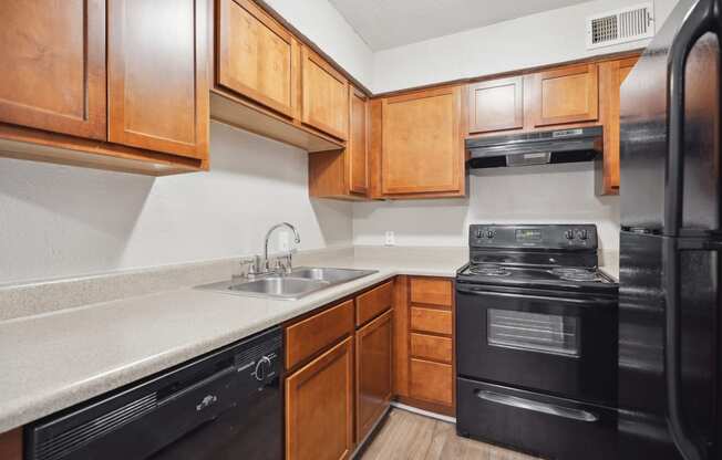 an empty kitchen with black appliances and wooden cabinets