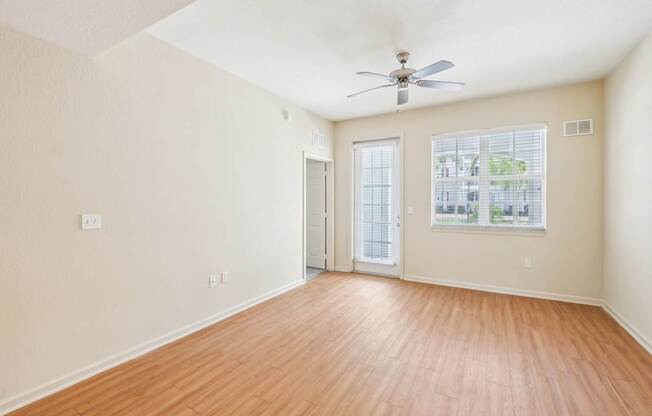 A room with a ceiling fan and wooden flooring.
