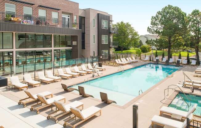 a swimming pool with lounge chairs and a building in the background