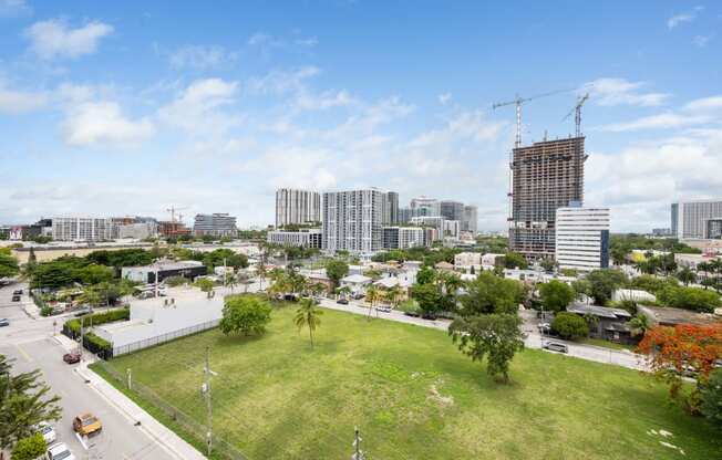 an aerial view of a grassy area with a tall building under construction in the background