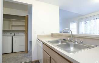 A kitchen with a white sink and a window with blinds.
