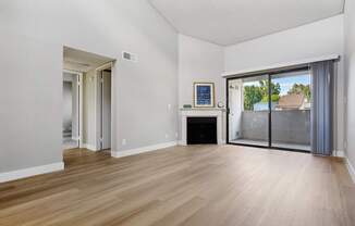 an empty living room with a fireplace and sliding glass doors