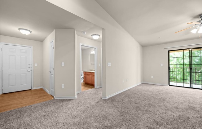 A spacious room with a ceiling fan and a sliding glass door.