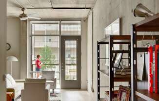 A person stands in a doorway with a plant in the background.