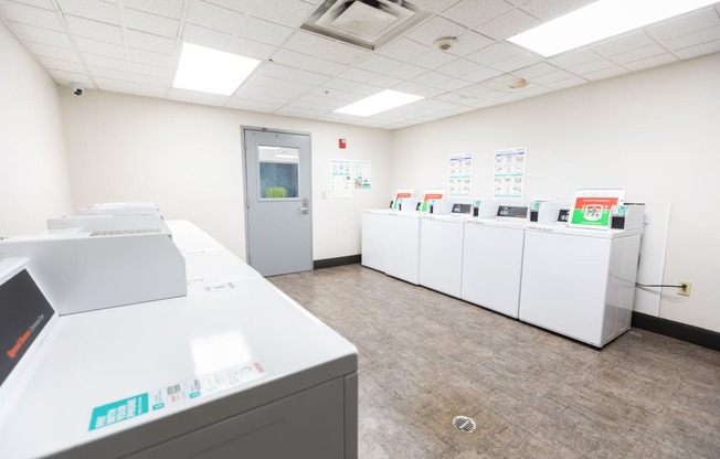 a laundry room with washers and dryers and a door to a hallway