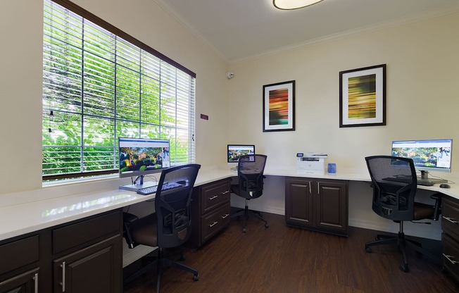 A room with three computers and two chairs.