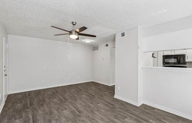A room with a ceiling fan and wooden flooring.