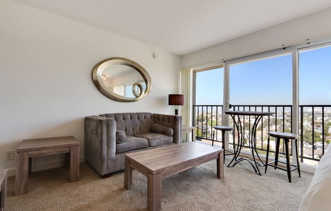 Living and dining area with carpet floors, large windows, balcony